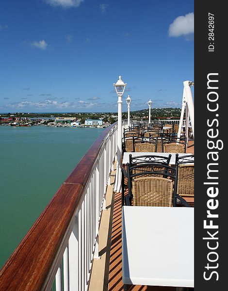 View of a cruise ship outdoor cafe with a view of a caribbean bay and coastal town. View of a cruise ship outdoor cafe with a view of a caribbean bay and coastal town.