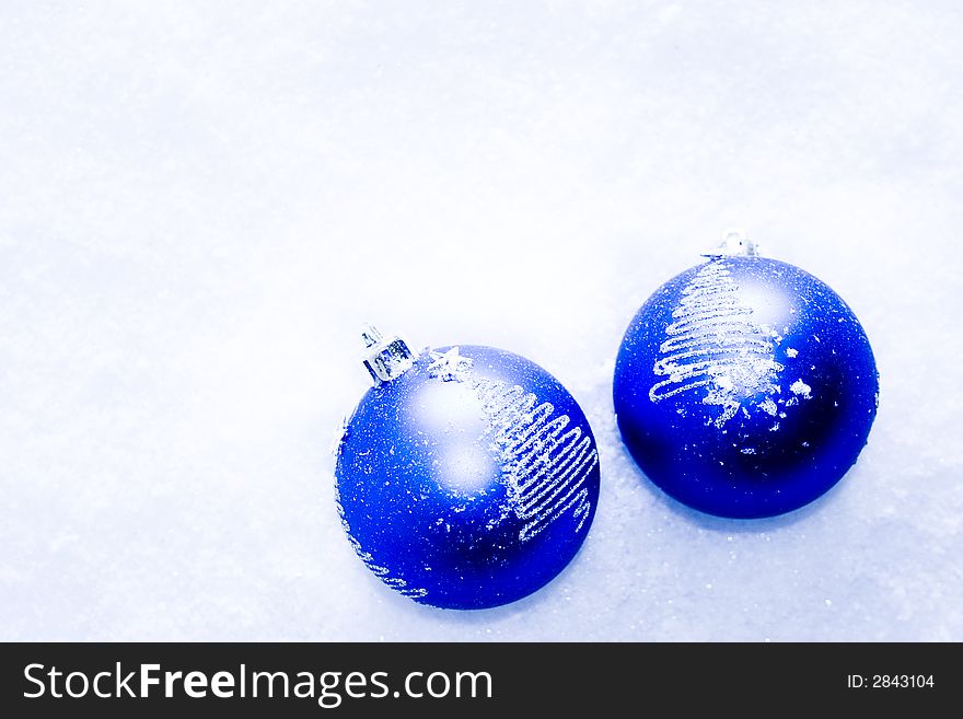 Two blue glass holiday ornaments in the snow. Two blue glass holiday ornaments in the snow.