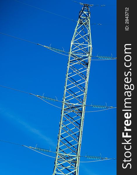 Power lines tower against a blue sky