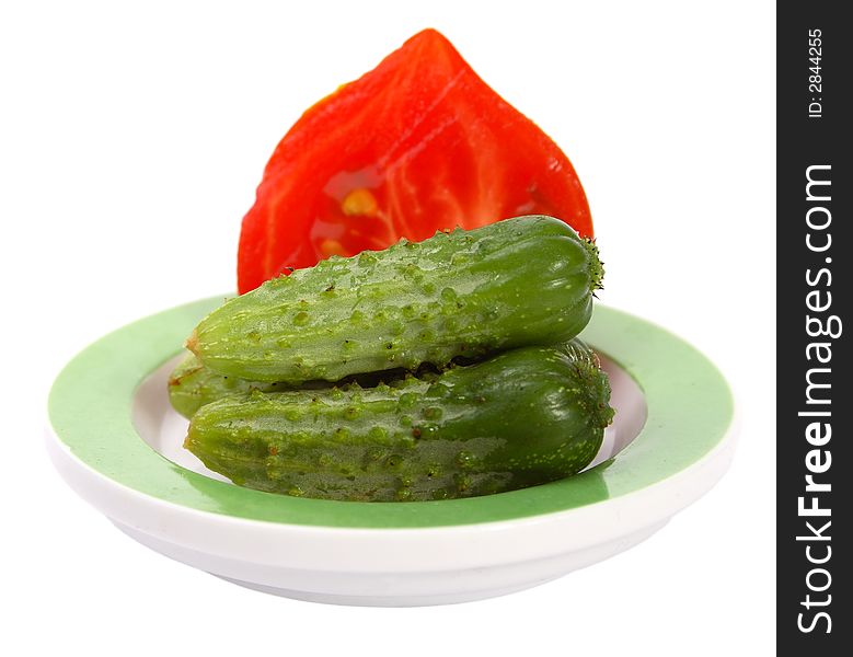 Three little cucumbers with the half of tomato on a dish. Three little cucumbers with the half of tomato on a dish