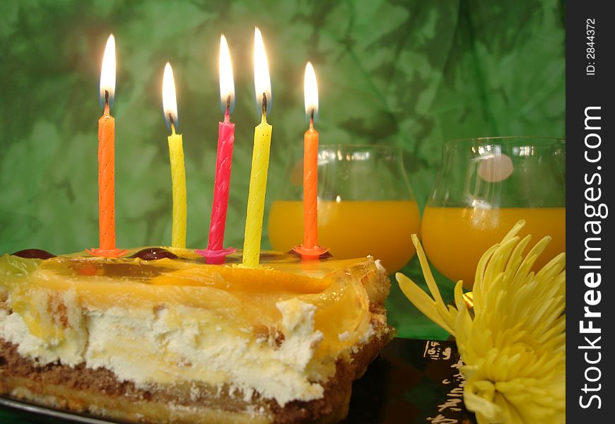 Celebratory table (cake and candles, two glasses) on green