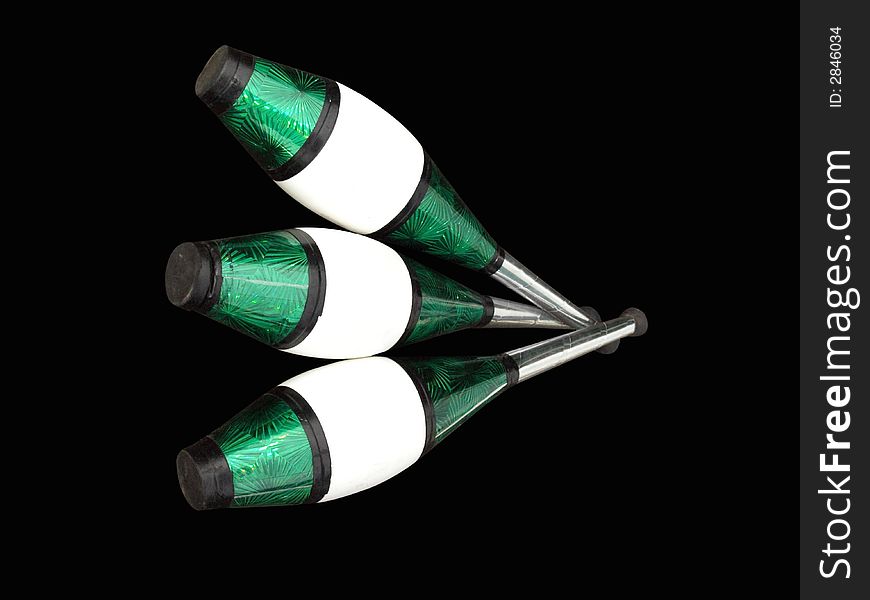 Three silver, green, black and white juggling clubs isolated on black background. Three silver, green, black and white juggling clubs isolated on black background