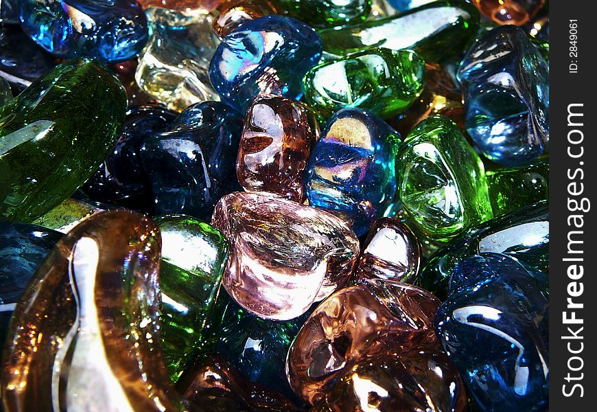 A bin of glass heart, star and moon shapes in various colors.  Focus is on a pink glass heart in the center. A bin of glass heart, star and moon shapes in various colors.  Focus is on a pink glass heart in the center