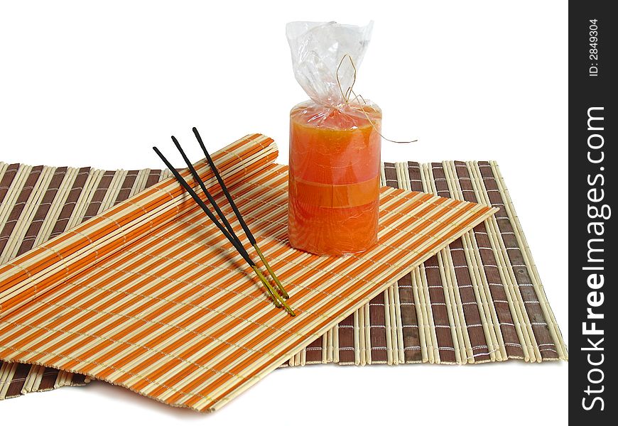 Aromas sticks and orange candle on bamboo mat