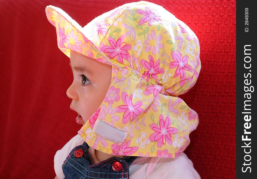 Baby girl in pink flower hat and bib overalls. Baby girl in pink flower hat and bib overalls.