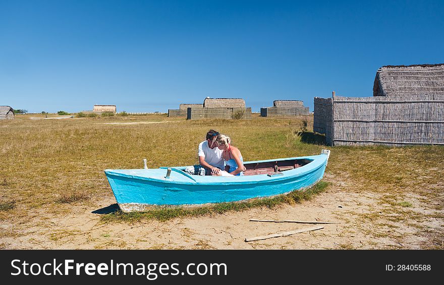 Cute young couple sitting in a old boat and kissing. Cute young couple sitting in a old boat and kissing