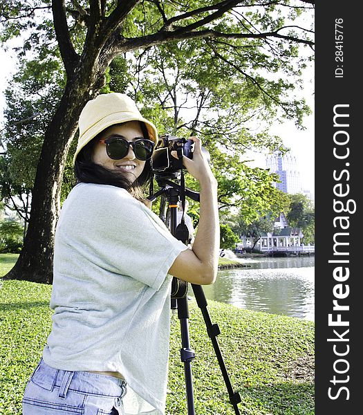 Beautiful smiling asian girl with camera on nature.