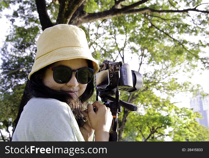 Smiling girl with camera on nature.