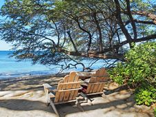 Two Wooden Adirondack  Chairs Overlooking Sandy Ocean Beach Stock Photo