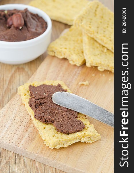 Crackers spread with chocolate paste on a wooden board. Crackers spread with chocolate paste on a wooden board