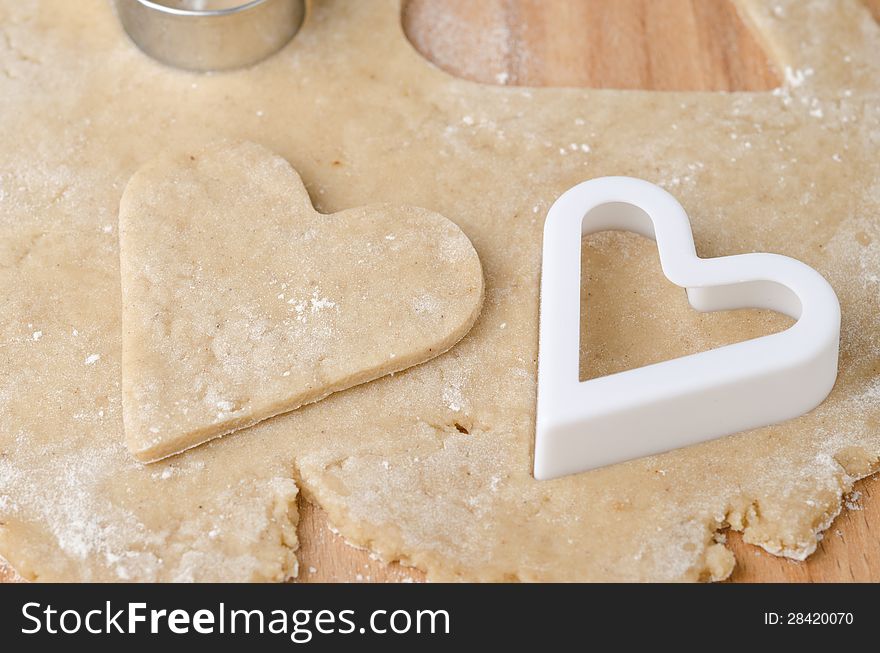 Heart shaped cookie cutter on raw cookie dough and a heart-shaped cutter closeup