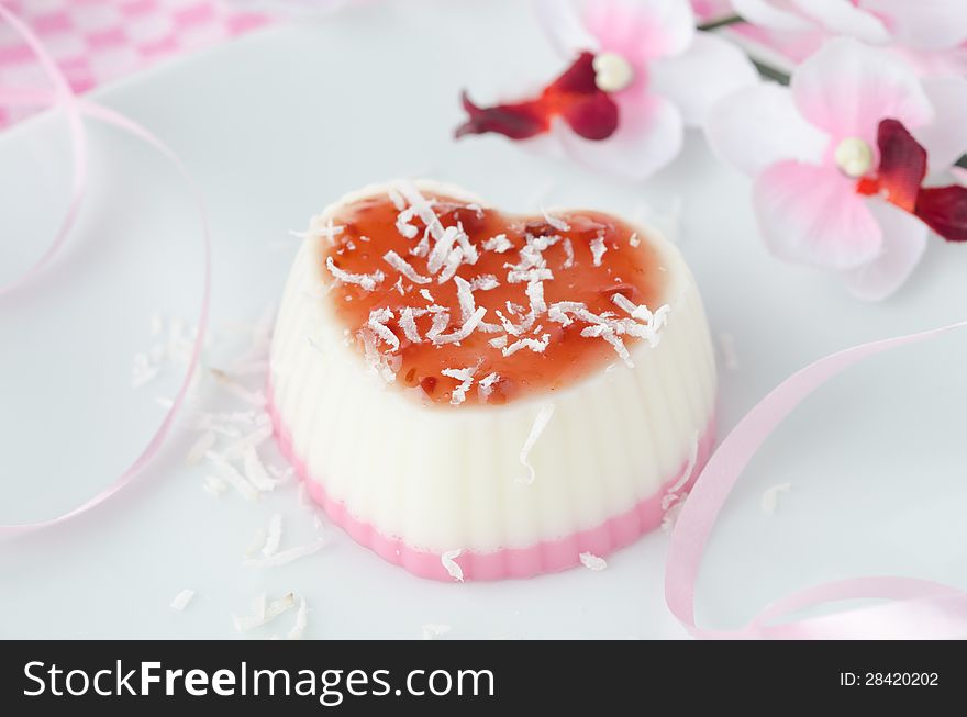 Two-layer dessert with coconut creamin the form of heart on white plate closeup. Two-layer dessert with coconut creamin the form of heart on white plate closeup