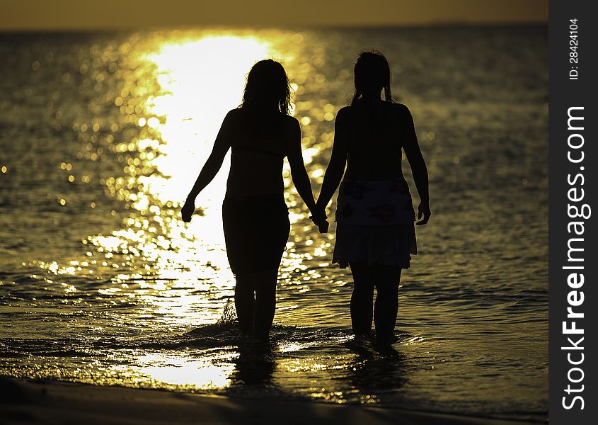 Two girls holding hands and going into the water. Two girls holding hands and going into the water