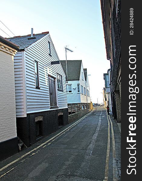 Photo showing narrow lane running between old fishermans huts and cottages in the historic harbour fishing town of whitstable in kent. Photo showing narrow lane running between old fishermans huts and cottages in the historic harbour fishing town of whitstable in kent.