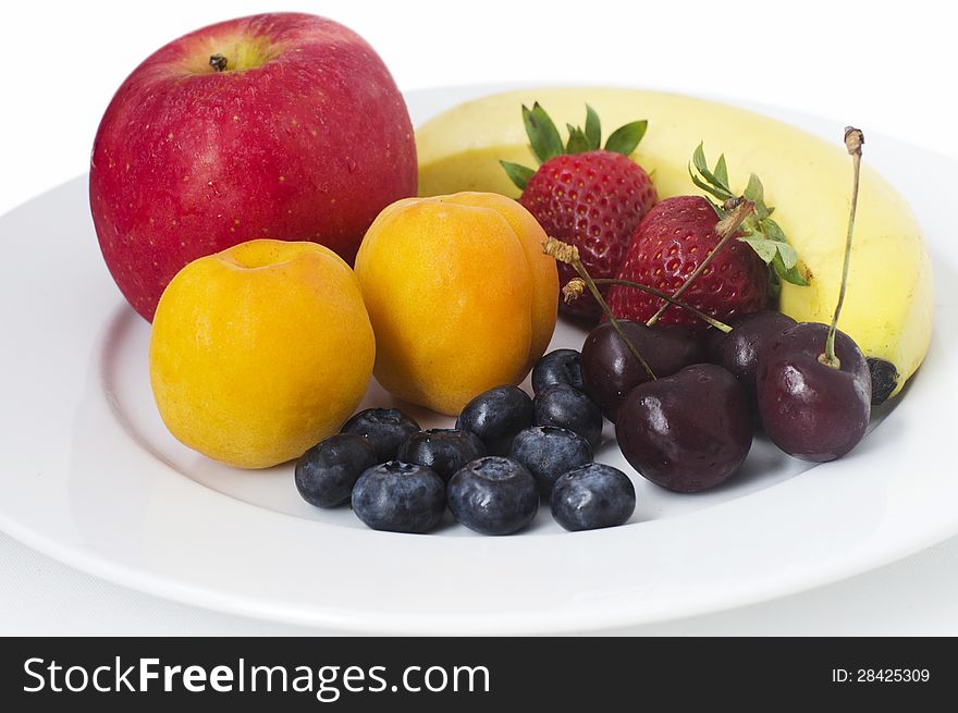 Summer fruits on a white plate on a white background.