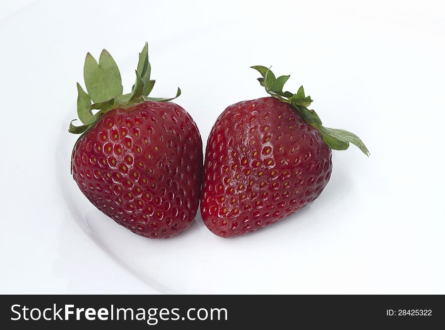 Two Strawberries on a white plate on a white background.