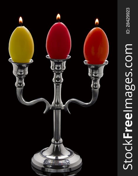 Three easter candles in the form of eggs in a candelabrum. Three easter candles in the form of eggs in a candelabrum.