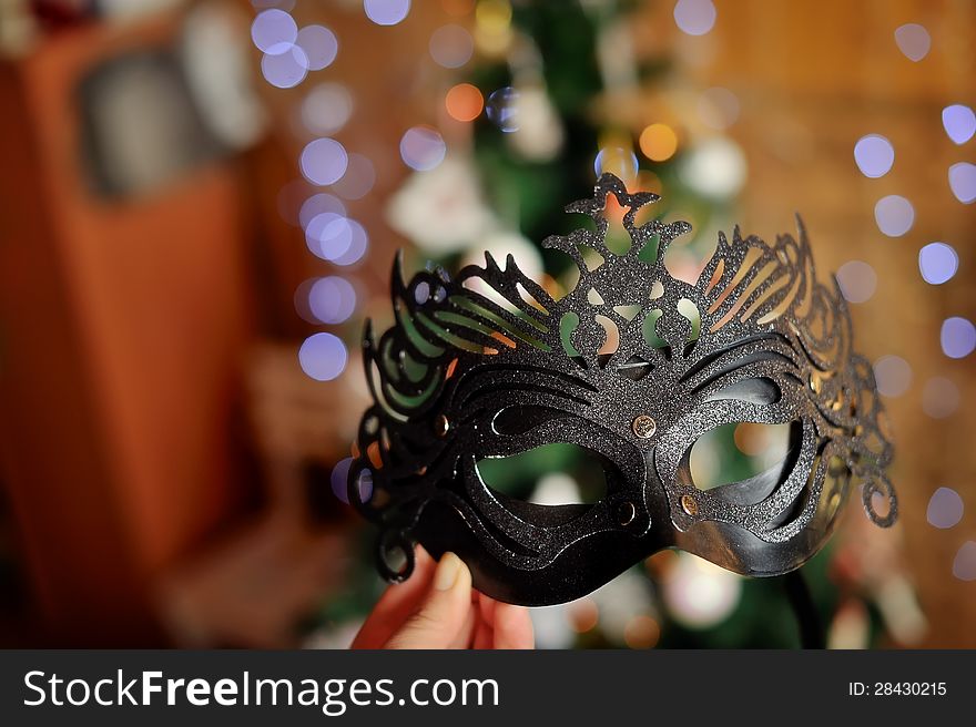Close up a beautiful black New Year's mask against a fur-tree. Close up a beautiful black New Year's mask against a fur-tree