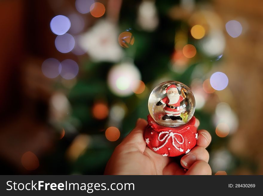 Against a New Year tree in a hand a sphere with Santa Claus. Against a New Year tree in a hand a sphere with Santa Claus