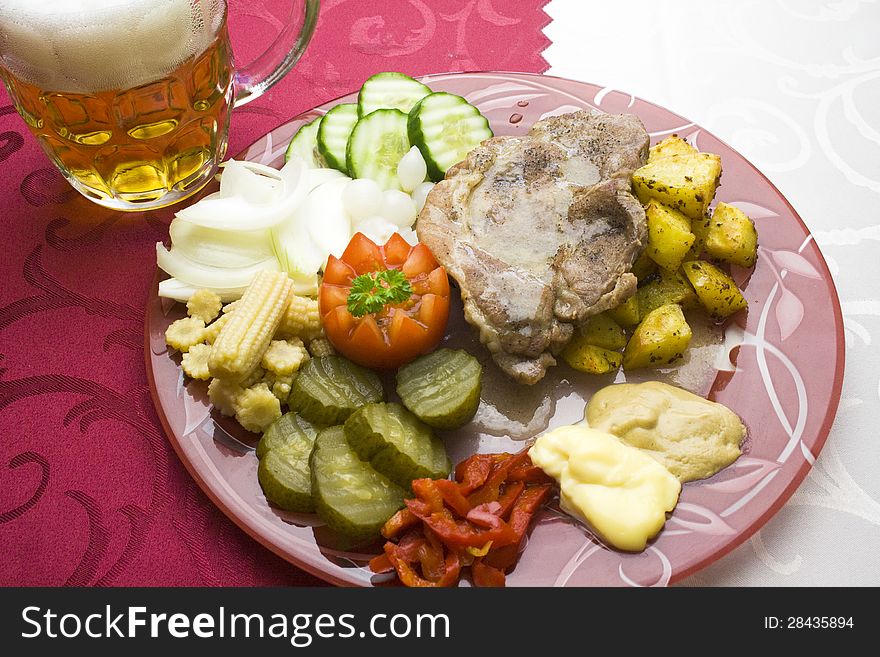 Vegetable garnish as an accompaniment to meat served on a plate with a glass of beer. Vegetable garnish as an accompaniment to meat served on a plate with a glass of beer