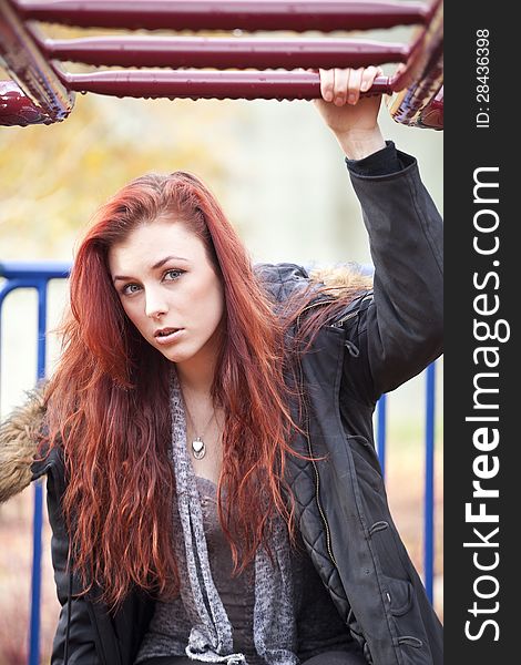 Young woman with beautiful red hair on playground equipment. Young woman with beautiful red hair on playground equipment.