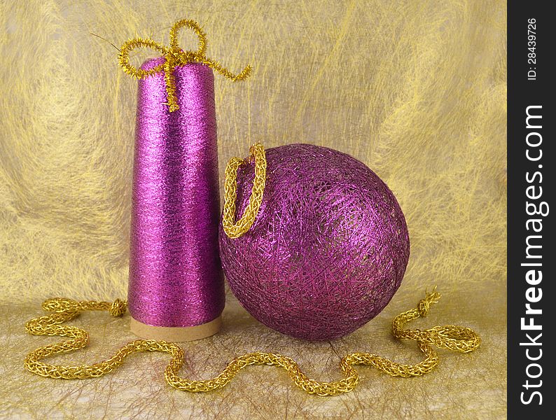 The shiny lilac ball made with the golden cord and sewing spool. The shiny lilac ball made with the golden cord and sewing spool