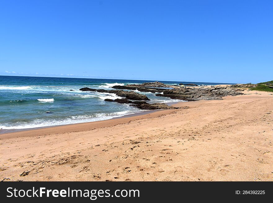 Shoreline With Rocks, Waves And Sand