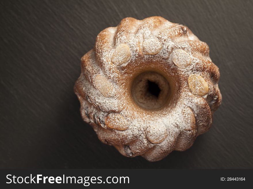 Topview of a cake garnished with almonds en powder sugar. on a dark background. With space for text. Topview of a cake garnished with almonds en powder sugar. on a dark background. With space for text.