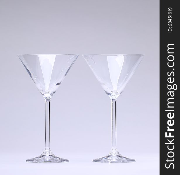 Two drinking glasses formed like a cone without flud in front of neutral light grey background. Two drinking glasses formed like a cone without flud in front of neutral light grey background