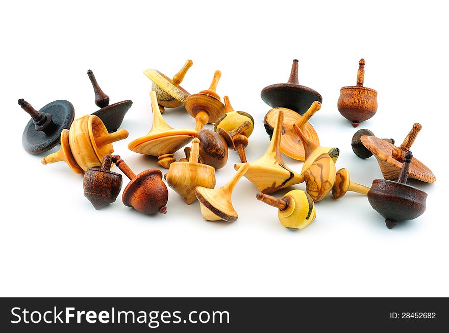 Spinning tops of different shapes, carved from wood, photographed against a white background