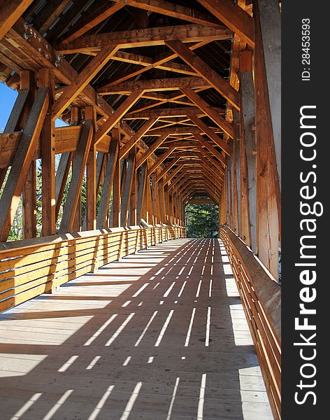 An inside view of the beams and angles of a wooden pedestrian bridge.