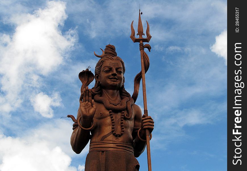 Shiva statue at GAnga Talao against the blues sky and clouds in Mauritius.