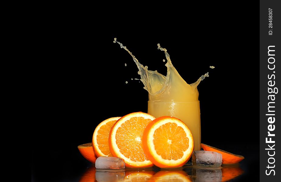 Glass of splashing orange juice on black background