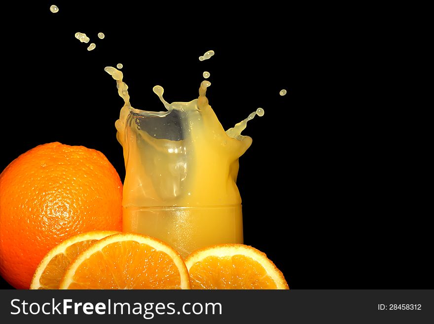 Glass of splashing orange juice on black background