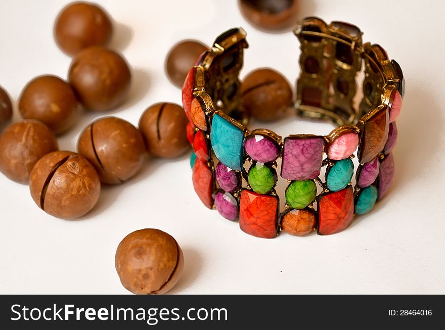 Colorful bracelet near macadamia nuts.
