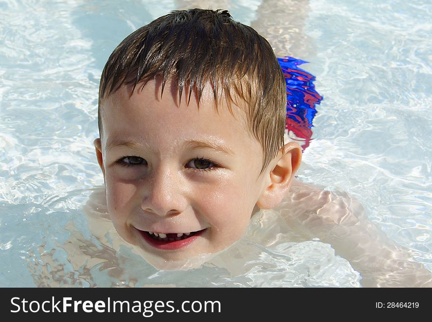 A close-up of a happy young boy swimming in the pool on holidays. A close-up of a happy young boy swimming in the pool on holidays.