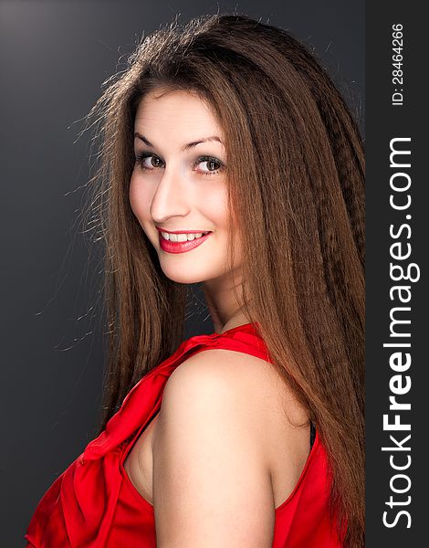 Portrait of a beautiful woman in a red dress and a snow-white smile