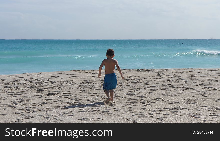 Little boy walking to the water toward the ocean in Miami Beach, Florida. Little boy walking to the water toward the ocean in Miami Beach, Florida