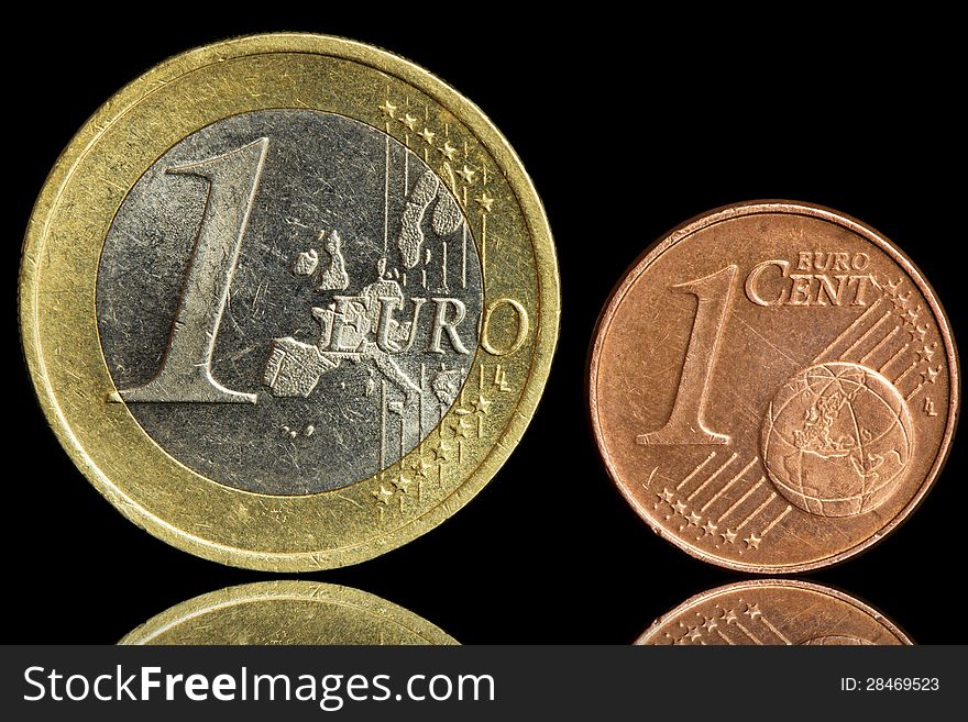 Two used coin - one euro and one euro cent - isolated on black background. Closeup view. Two used coin - one euro and one euro cent - isolated on black background. Closeup view.
