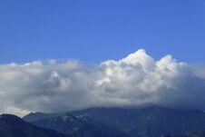 Large Great White Cumulus Clouds In The Blue Sky Over The Mountains Of The Trans-Ili Alatau, Covering Their Peaks, Are Brightly Li Stock Photos