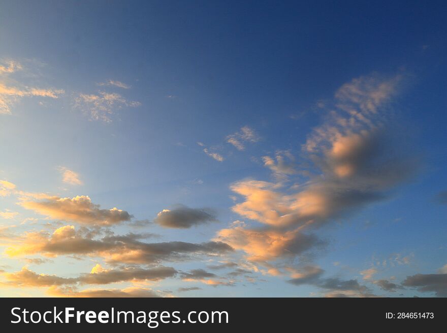 Light Cirrus Small Orange Clouds In The Blue Sky Are Illuminated By The Morning Sunlight.