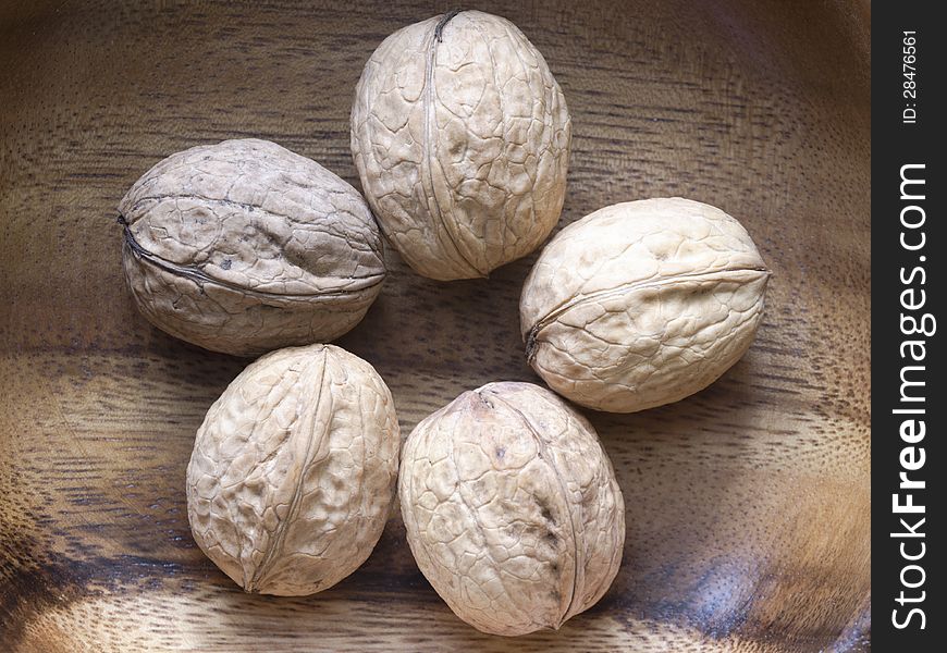 Five ripe walnuts on wooden background