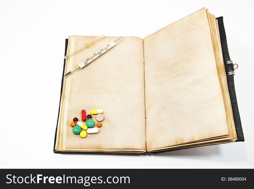 Tablets and thermometer on the old book. Tablets and thermometer on the old book