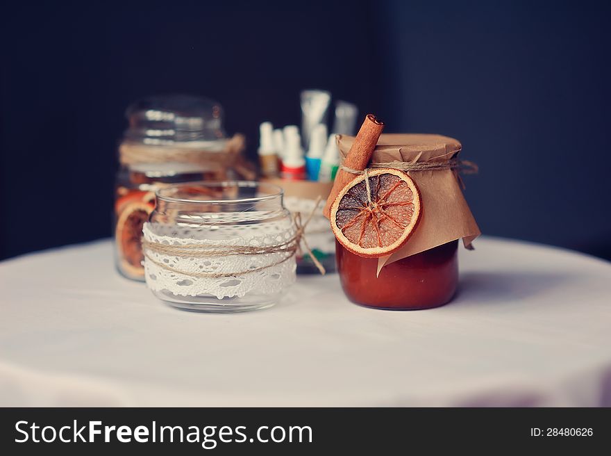 On a white table there are beautiful banks with jam