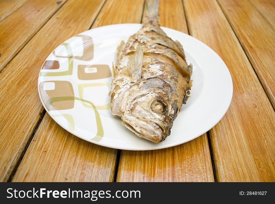 Fried fish on white dish and wood background, delicious thai food