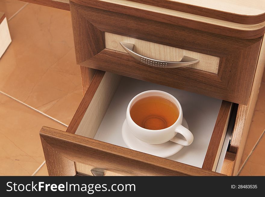 Cup of tea in open desk drawer. Cup of tea in open desk drawer