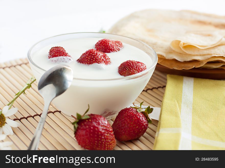 Strawberry yogurt and a plate of pancakes