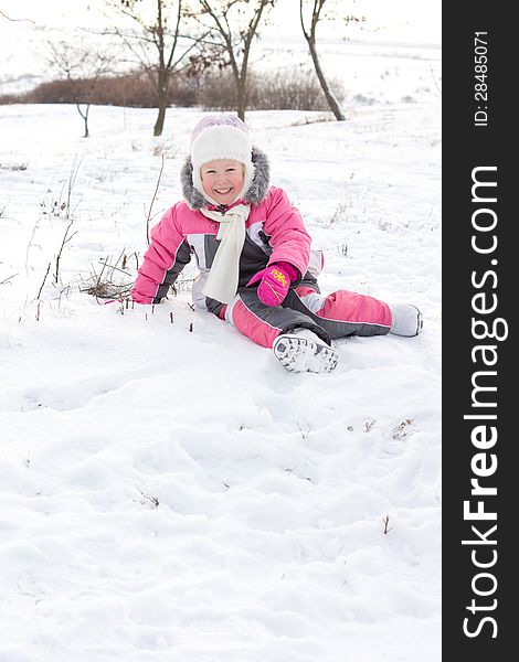 Cute little girl with a beautiful smile wearing a cuddly punk outfit and cap frolicking in winter snow with copyspace. Cute little girl with a beautiful smile wearing a cuddly punk outfit and cap frolicking in winter snow with copyspace