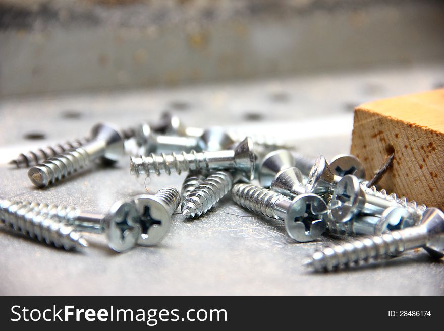 Metal Screws on Natural Construction Site with wood and a nail in the backround. Metal Screws on Natural Construction Site with wood and a nail in the backround