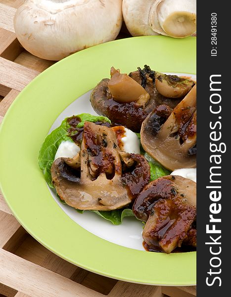 Cooked Mushrooms with Grill Sauce, Sour Cream and Greens on Plate closeup on Wood background and Raw Mushrooms